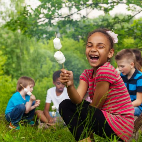 Laughing African girl holds stick with smores